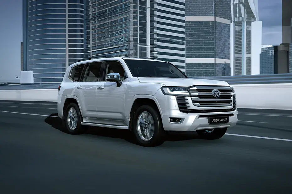 White Toyota Land Cruiser driving past city towers