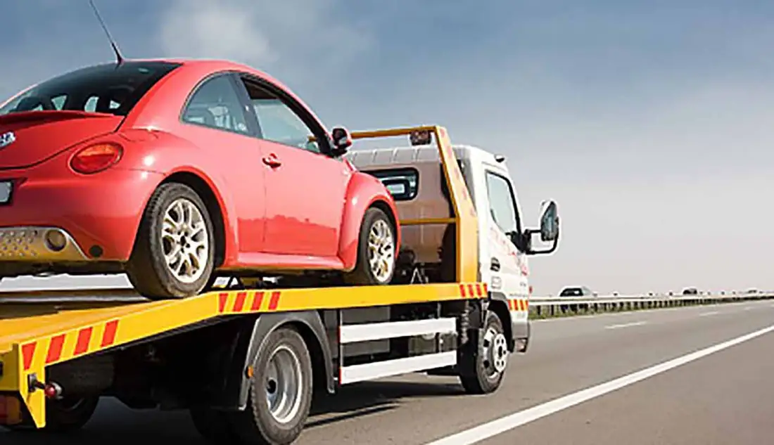 Red car loaded on a flatbed tow truck